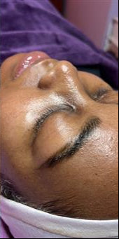 Side-by-side comparison of a person's face with and without makeup, wearing a purple garment.