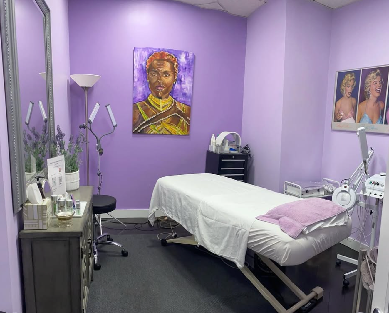 Medical spa room with purple walls, a bed, and medical equipment.